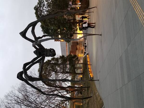 Statue of huge spider towering over some people